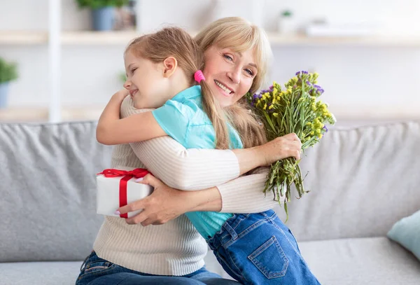 Mutlu küçük çocuk çiçekli mutlu yaşlı kadını selamlıyor.