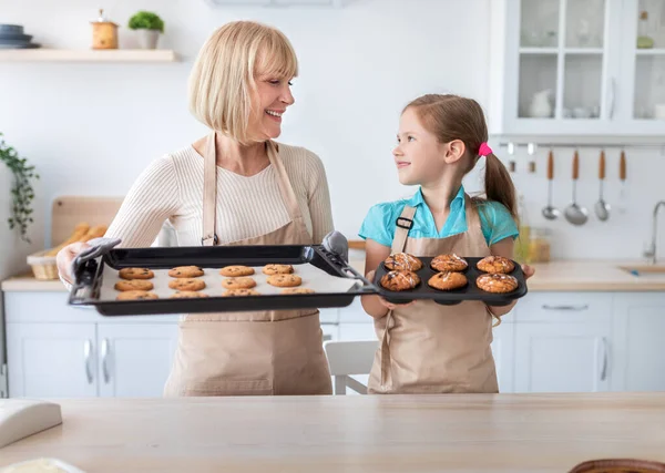 Boldog idős nő és unokája sütit mutat — Stock Fotó