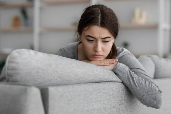 Oberörd upprörd frustrerad europeisk ung kvinna sitter på soffan tittar på tomhet hemma — Stockfoto