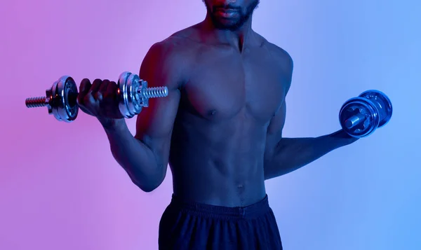 Bodybuilding en krachttraining. Onherkenbare zwarte man met kale romp training met halters in neon licht — Stockfoto