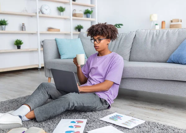 Estudante adolescente preto fazendo projeto educacional para o curso on-line, beber café em casa — Fotografia de Stock
