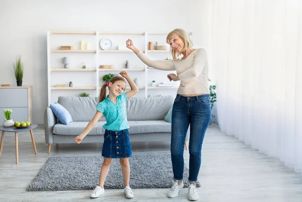 Alegre abuela bailando a la música con linda niña —  Fotos de Stock