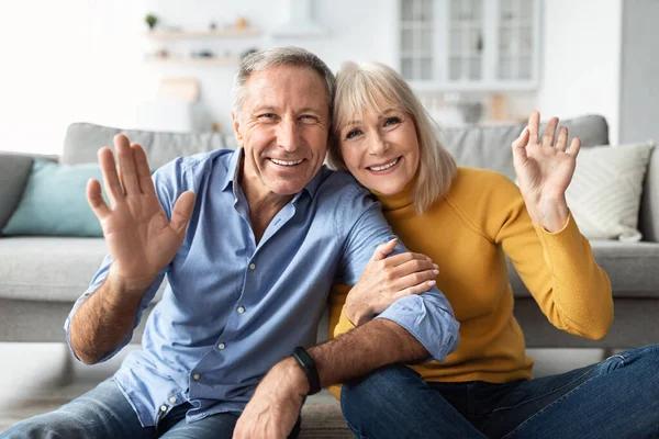 Cheerful Older Couple Waving Hands To Camera Sitting At Home — Stock Photo, Image