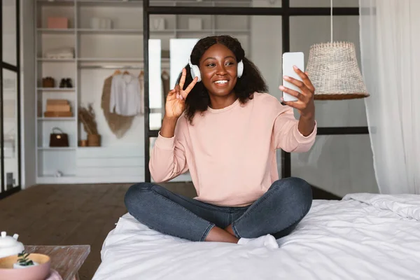 自宅でヘッドフォンを着用して携帯電話でセルフィーを作る黒人女性 — ストック写真