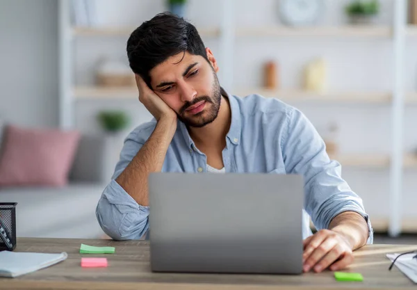 Overworked young freelancer man sitting at workplace and sleeping, napping while working on laptop, copy space — Stock Photo, Image