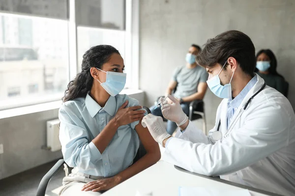 Paciente femenina mirando al médico guapo mientras recibe la vacuna —  Fotos de Stock