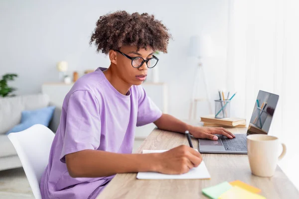 Skupienie czarny nastolatek robi notatki podczas wykładu online na laptopie w domu, wolne miejsce — Zdjęcie stockowe