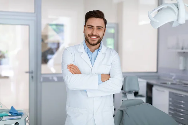 Fiatal férfi fogorvos pózol a fogorvosi szekrényben — Stock Fotó