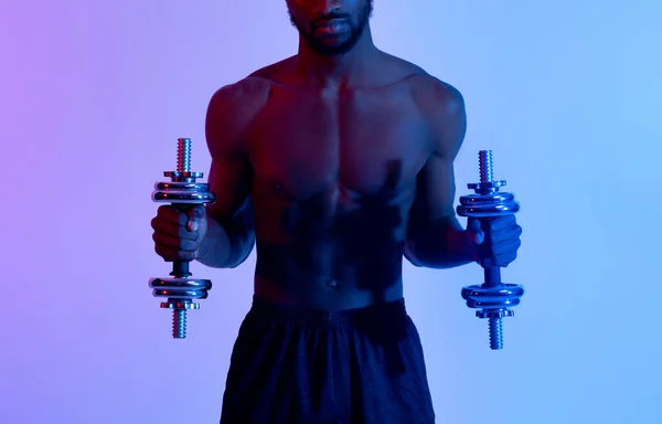 Unerkennbarer schwarzer Gewichtheber mit nacktem Oberkörper beim Training mit Kurzhanteln im Neonlicht, Panorama — Stockfoto