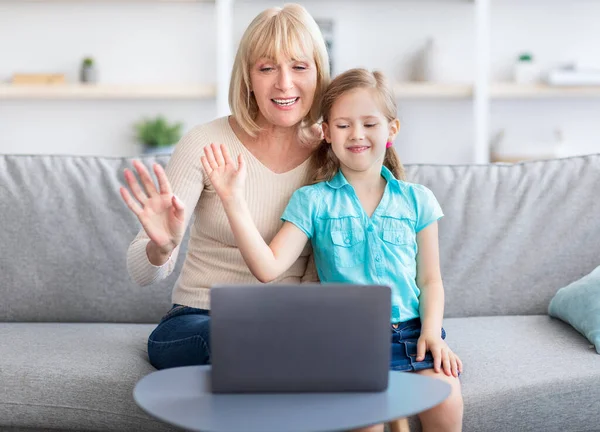Senior woman and girl having videocall using laptop waving hands — Stock Photo, Image