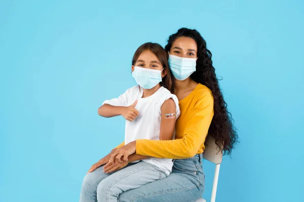 Vacunado árabe chica y su mamá gestos pulgares-up, fondo azul —  Fotos de Stock
