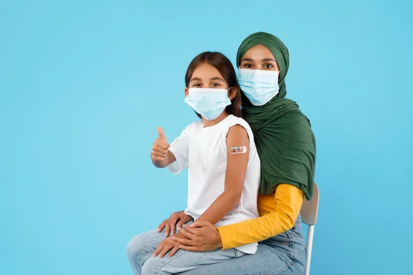Madre Islámica Vacunada e Hija Gestos Pulgares Arriba Sobre Fondo Azul —  Fotos de Stock