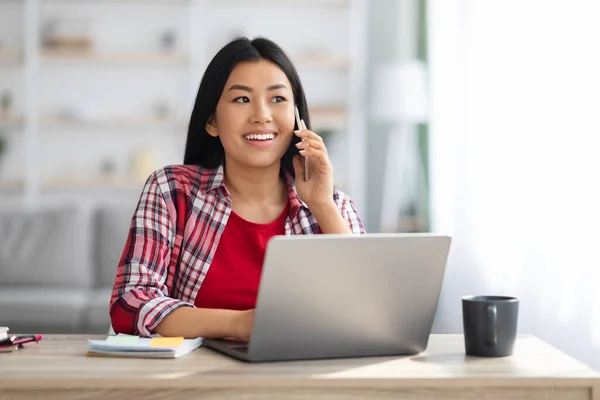 사무실 컨셉. 젊은 아시아 여성 이 전화로 이야기하고 노트북을 사용하는 모습 — 스톡 사진