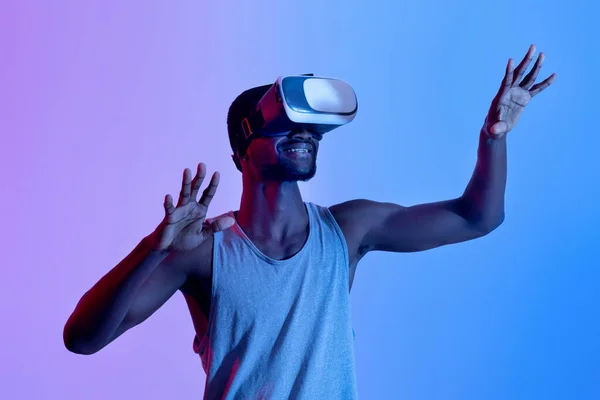 Sportowy czarny sportowiec noszący słuchawki VR, mający wirtualny trening w rozszerzonej rzeczywistości, oświetlenie neonowe — Zdjęcie stockowe