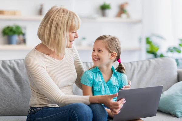 Szczęśliwy dojrzałe kobieta i wnuczka za pomocą laptopa w salonie — Zdjęcie stockowe