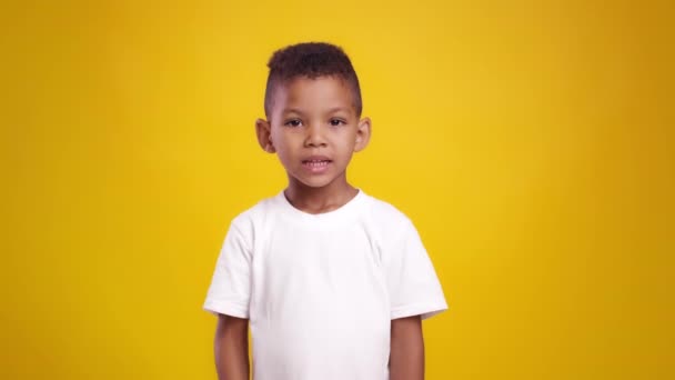 Shh, het geheim. Schattig Afrikaans amerikaans jongen putting vinger op lippen, tonen privacy gebaar naar camera, oranje achtergrond — Stockvideo