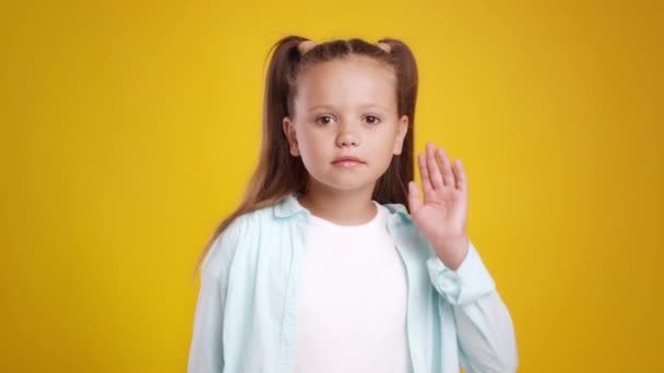 Kinderen en kletspraat. Nieuwsgierig meisje dat roddels hoort, hand in hand bij haar oor houdt en opzij leunt, oranje achtergrond — Stockvideo