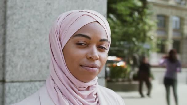 Feliz positivo musulmán africano americano mujer de negocios usando hijab sonriendo ampliamente a la cámara, posando al aire libre — Vídeos de Stock
