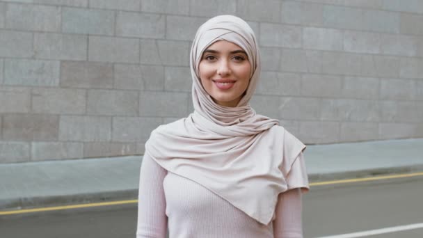 Estilo de vida positivo. Jovem feliz pacífica senhora do Oriente Médio vestindo tradicional hijab sorrindo para câmera ao ar livre — Vídeo de Stock