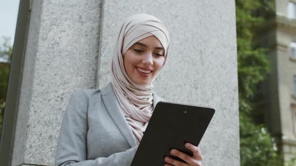 Conceito de economia de gig. Jovem mulher de negócios muçulmano confiante vestindo rede hijab em tablet digital ao ar livre — Vídeo de Stock