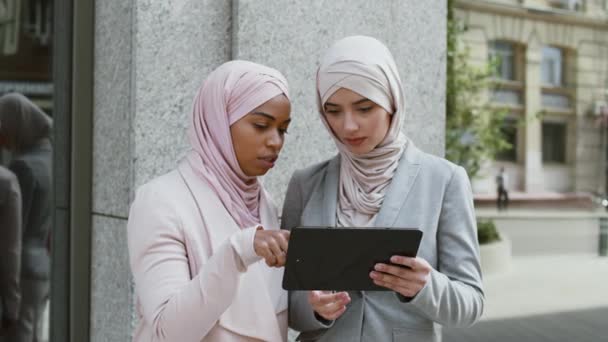 Des négociations commerciales modernes. Deux femmes musulmanes diverses partenaires commerciaux étudiant la stratégie de marketing sur tablette numérique — Video