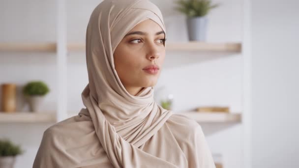 Retrato de una joven mujer musulmana de Oriente Medio confiada usando el hiyab tradicional girando hacia la cámara y sonriendo en casa — Vídeos de Stock