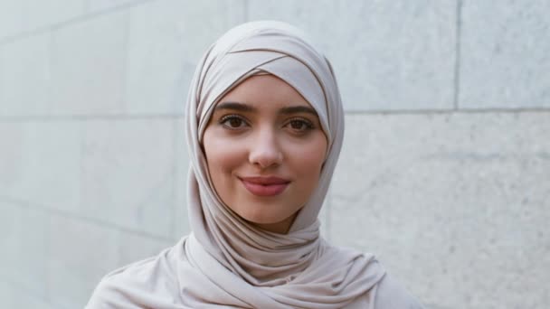 Ближневосточная красота. Закрыть на улице портрет беззаботной спокойной молодой мусульманки в хиджабе, улыбающейся в камеру — стоковое видео