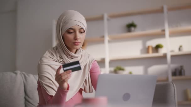 Transaktionskoncept online. Ung Mellanösternkvinna i traditionell hijab shopping online med kreditkort och bärbar dator — Stockvideo