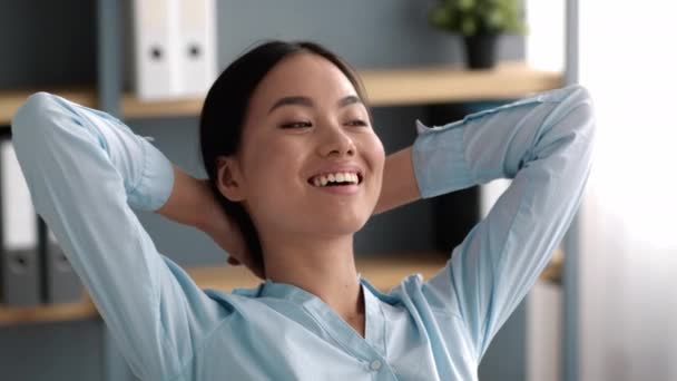 Успішна азіатська ділова жінка розслаблює руки, тримаючи їх за голову — стокове відео