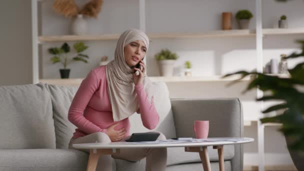 Appel d'urgence. Jeune femme musulmane enceinte inquiète ressentant une douleur à l'estomac et appelant son médecin pour consultation — Video