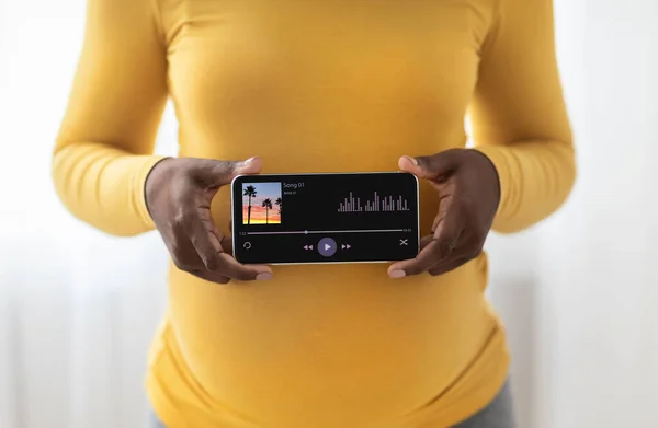 Gravidez Música App. preto grávida senhora segurando smartphone com leitor de música aberta — Fotografia de Stock