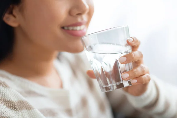 Hydrationskoncept. Closeup shot af smilende ung dame drikker vand fra glas - Stock-foto
