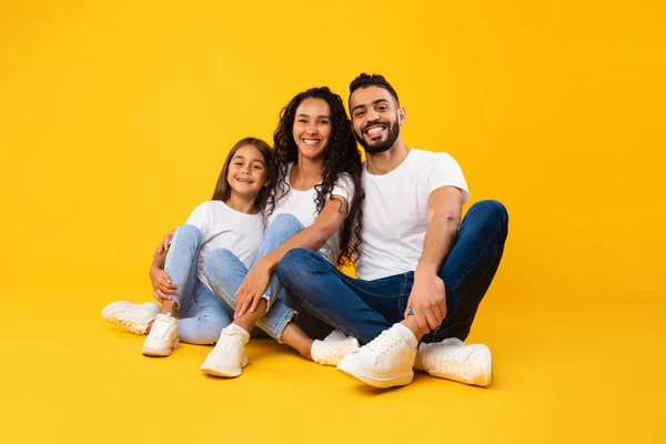 Щасливий арабський батько, мати і дочка, які вишиковують сидіння, жовте тло — стокове фото