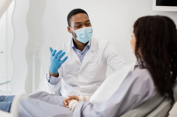 Serviços dentários. Retrato do médico estomatologista preto que consulta o paciente fêmea na clínica — Fotografia de Stock