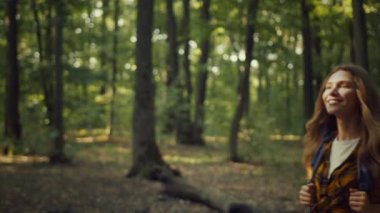 Şirin, mutlu, aktif bir kadının portresi. Doğanın güzelliğinin tadını çıkarıyor. Sıcak sonbahar ormanlarında ekipmanlarla sırt çantasıyla geziyor.