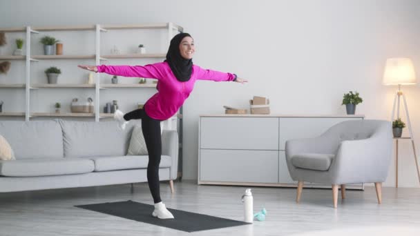 Entrenamiento de equilibrio. Joven mujer musulmana positiva de Oriente Medio con pañuelo de cabeza tradicional practicando ejercicio de equilibrio — Vídeos de Stock