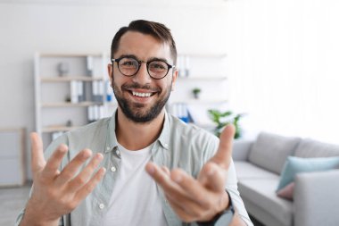 Gözlüklü sakallı, gülümseyen, yetişkin Avrupalı bir erkek kameraya bakıyor ve blog için video çekiyor.