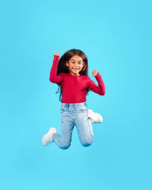 Küçük Kız Mavi Arkaplanda, Havada Eğlenceli Pozlar Veriyor