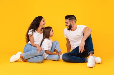 Neşeli Orta Doğulu Aile konuşuyor ve gülüyor Sarı arka planda oturuyor