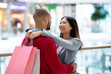 Alışveriş torbalarıyla harika bir çift. Büyük markette birbirlerine sarılıp bakıyorlar.