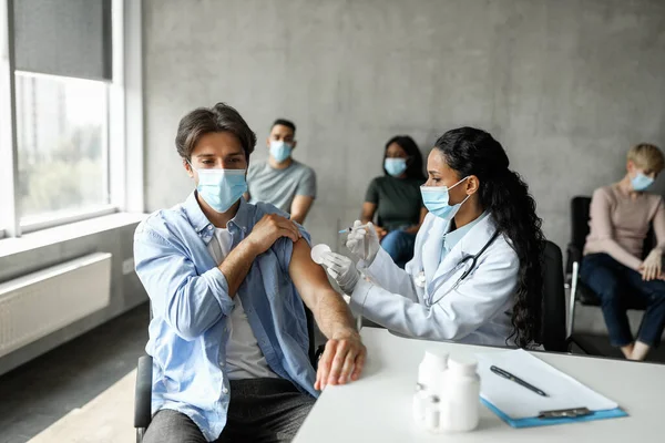 Hombre milenario recibiendo inyección intramuscular en el hombro, vacunación mientras pandemia —  Fotos de Stock