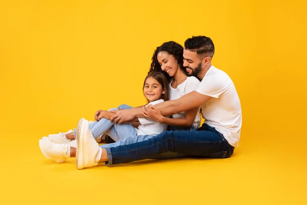 Vista lateral do abraço da família do Oriente Médio sentado sobre fundo amarelo — Fotografia de Stock
