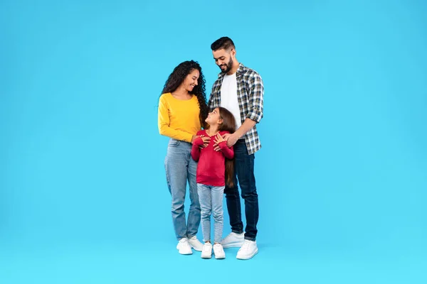 Pais do Oriente Médio abraçando sua filha feliz em fundo azul — Fotografia de Stock