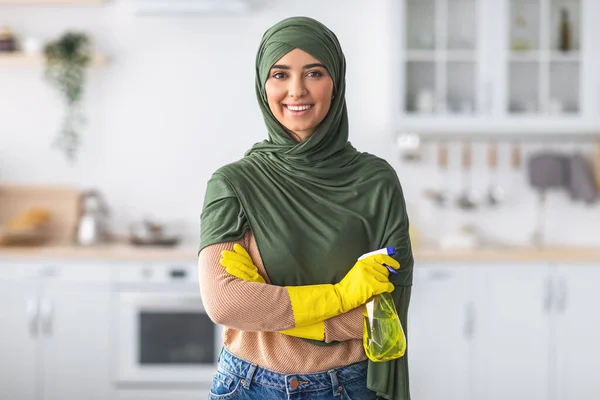 Alegre jovem islâmico dona de casa segurando spray garrafa posando na câmera — Fotografia de Stock
