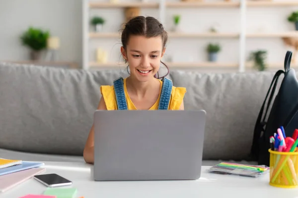 Meisje zit op de bank met behulp van laptop thuis — Stockfoto