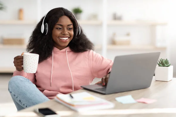 Joyful negro dama viendo película en línea, utilizando el ordenador portátil en casa — Foto de Stock