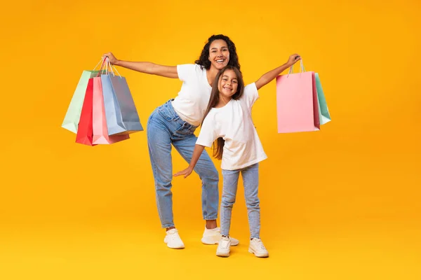 Mãe árabe e filha compras segurando sacos de compras, fundo amarelo — Fotografia de Stock