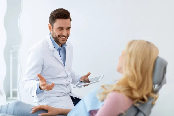 Homem dentista alegre ter conversa com paciente mulher loira — Fotografia de Stock