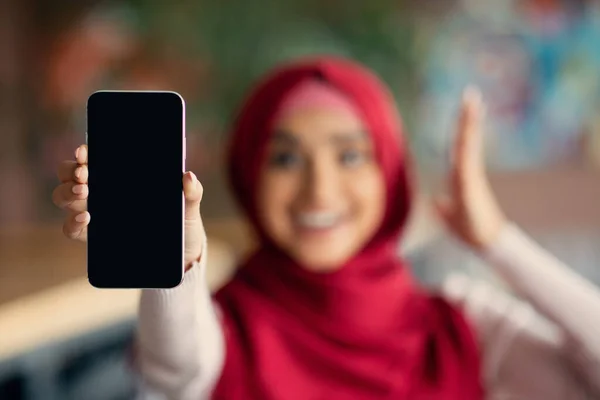 Religious woman showing cellphone with empty screen, mockup
