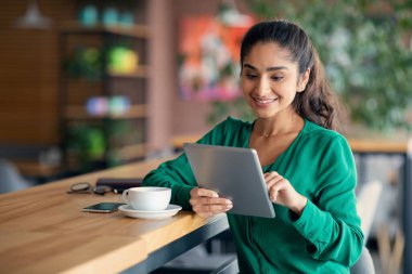 Orta doğulu güzel bir kadın kafede yemek molası veriyor, ped kullanıyor.